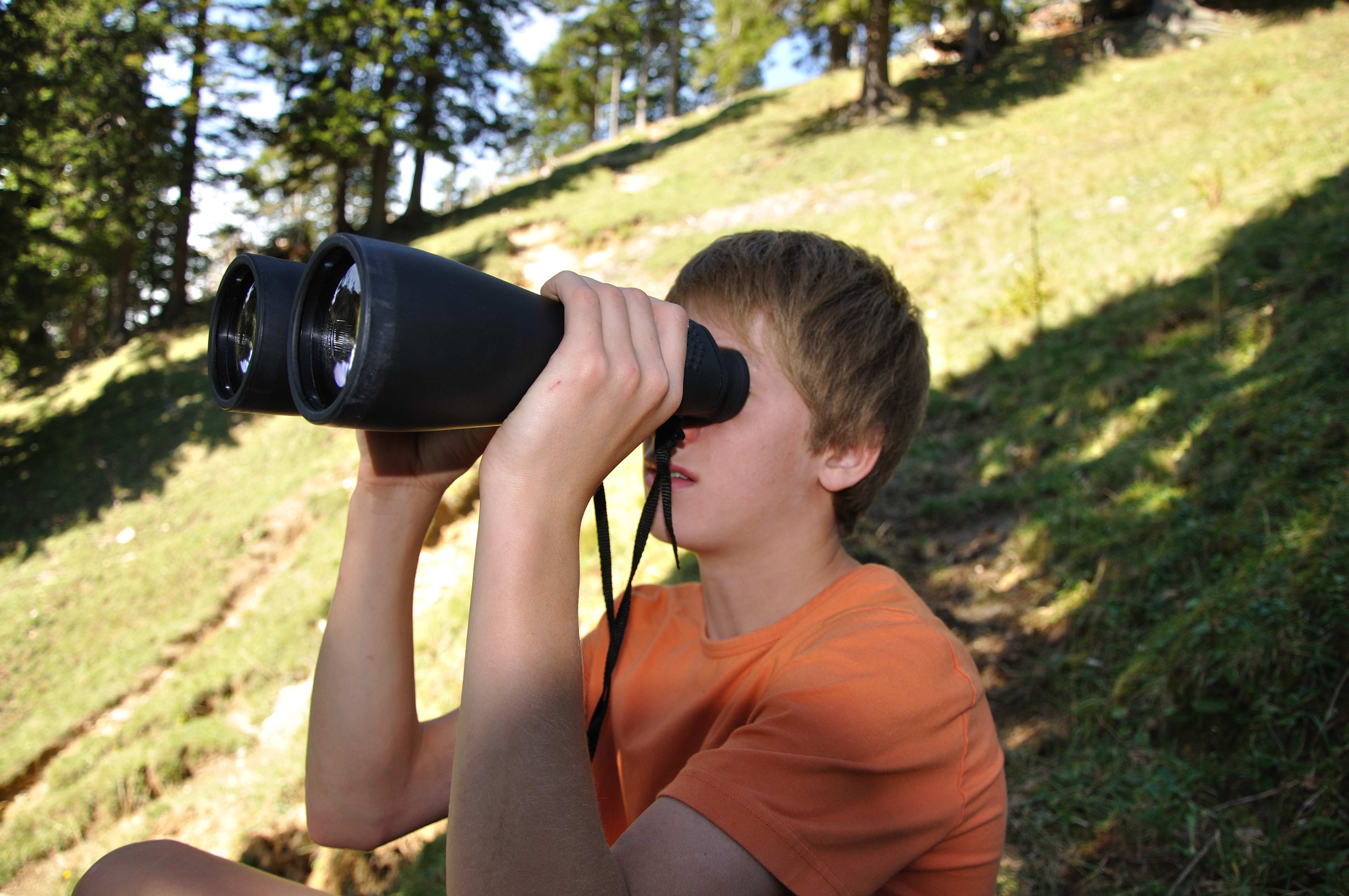 Ein Junge schaut durch ein Fernglas in die Natur
